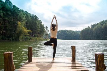 Healthy woman practicing yoga on the bridge in the nature
