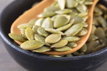 Close-up green pumpkin seeds in a black cup, snack for healthy a