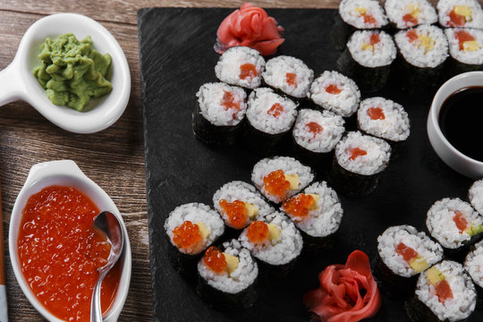 sushi rolls and ingredients served on a wooden surface