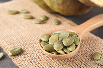 Green pumpkin seeds in a wooden spoon, snack for healthy and sli