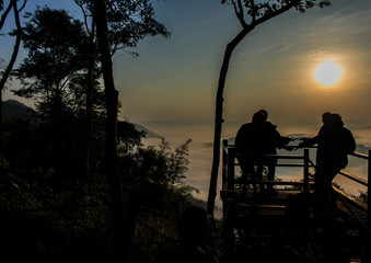 Fototapeta na wymiar Silhouettes of tourists on viewpoint with the mountain in mornin