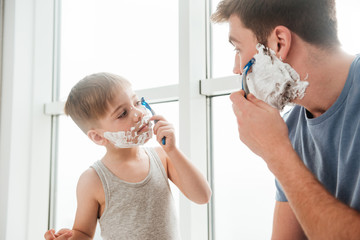 Father and son are shaving in bathroom