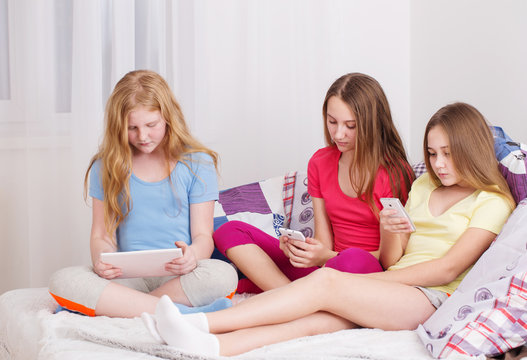 happy girls with smartphone and tablet pc at home