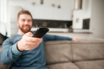 Young man holding remote control while watching TV