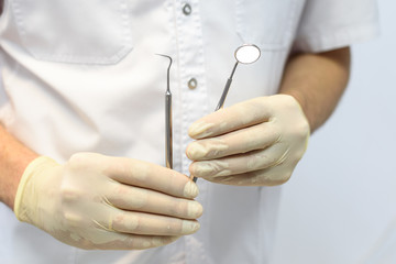 hands of dentist holding his tools during patient examination