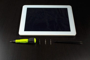 The tablet computer and a screwdriver. Repair Tablet PC.