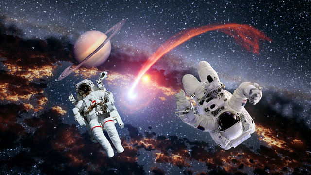 Two astronauts planet Saturn spaceman comet space suit galaxy universe. Elements of this image furnished by NASA.