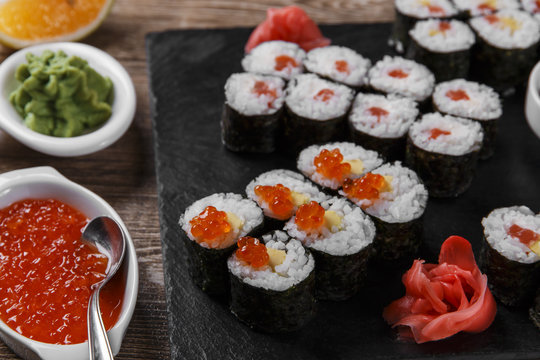sushi rolls and ingredients served on a wooden surface