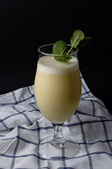 Cocktail of pineapple colada with mint on a cloth and the black background
