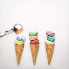 Colored pastry / Creative still life photo of three waffle cones with macaroons and spoon on grey background.