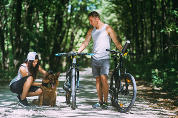 Obraz premium Cyclists young couple walking in the park with a dog
