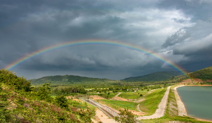 Fototapeta na wymiar rainbow on dam and mountain background