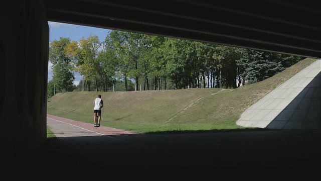 Silhouette of jumping athlete from the shadow of bridge to the open space with bright sun light.