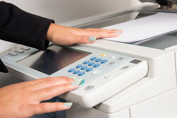 Close up of office printer and woman's hand using it.