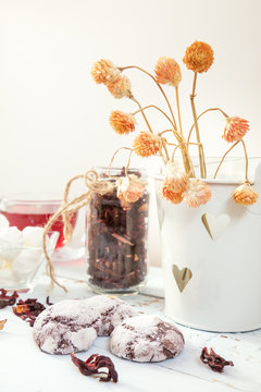 Chocolate crinkles cookies, marshmallows, Hibiscus tea, dried flowers on a light wooden table against white background. Coloring and processing photo.