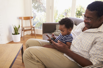 Grandfather And Grandson At Home Using Digital Tablet