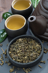 green tea in a ceramic bowl and tea utensils, vertical
