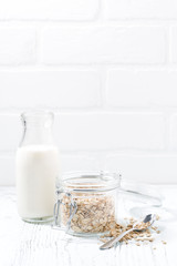 oat flakes and bottle of milk and white background, vertical