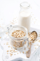 oat flakes and bottle of milk on white wooden background