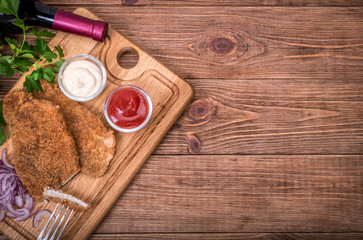 Pork schnitzel with sauce on the wooden board.