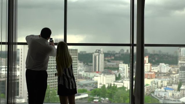 Man and woman stand near a window.
