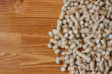 Biofuel - small wooden pellets over the wooden table.