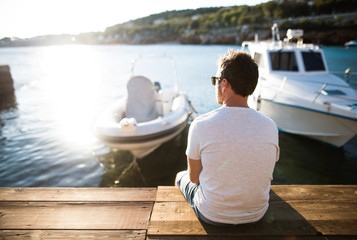 Man enjoying time at seaside, sitting on wooden pier.