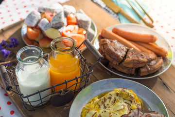 Fototapeta na wymiar Colourful breakfast table with fruits egg and sausage, orange juice and milk 