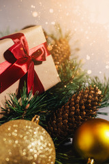 New Year's gift, toy, card, cones. New Year composition on gray concrete background. Snowflakes in the foreground. Warm light in the corner.