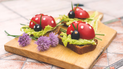 Sandwich in form of ladybird beetles made of fresh tomato, salad and bread. Funny children breakfast 