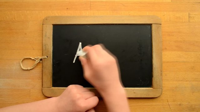 Kid is writing ABC on a chalkboard