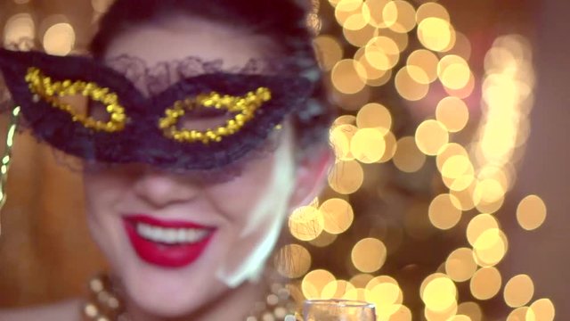 Beautiful sexy woman wearing venetian masquerade mask over holiday glowing background. Slow motion 240 fps. Full HD 1080p
