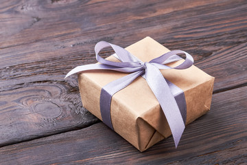 Present box on wooden surface. Ribbon bow on gift box. Template of a present.