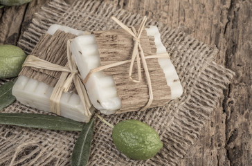 Olives and soap bars on wooden table