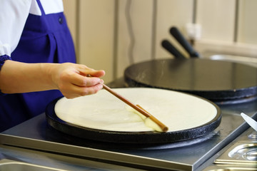 Close-up of cook frying crepe or pancake