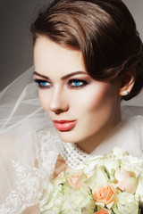 Portrait of young beautiful woman with bridal veil and bouquet of roses