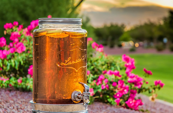Sun Tea brews with flowers and a summer sunset in the background