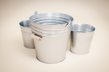 three metal buckets on a smooth beige background