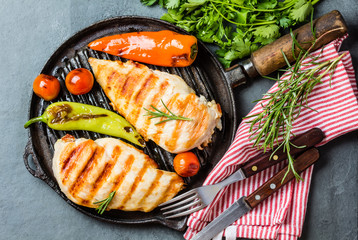 Grilled chicken fillets, chili and tomatoes on grill iron pan