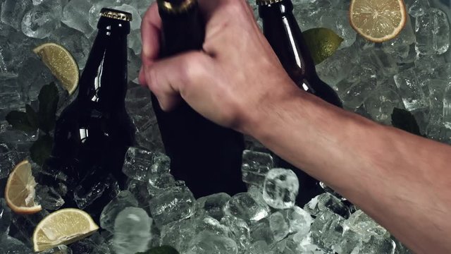 4k Shot of Cold Ice Cubes and Hand putting a Beer Bottle