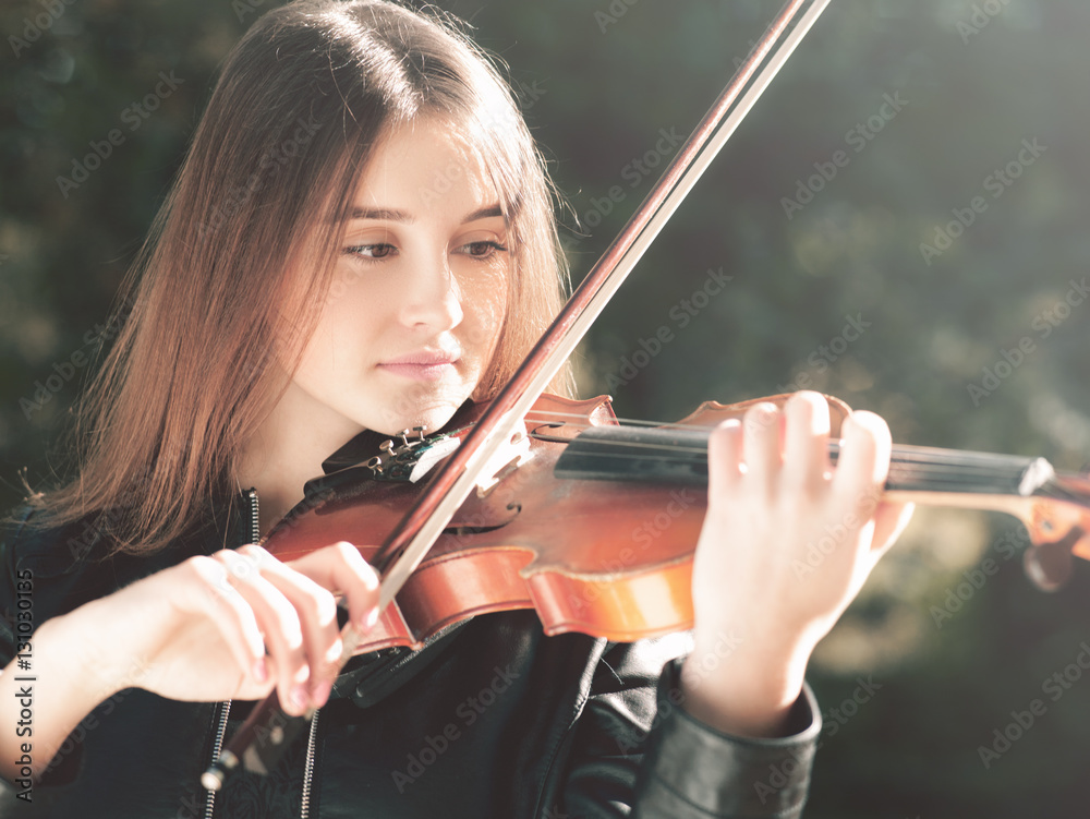 Wall mural Young beauty musician playing his violin, urban female portrait