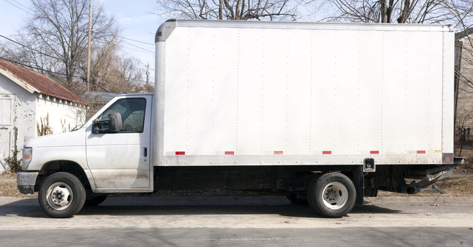 Side View Of White Delivery Van Parked On Residential Neighborhood Street. Horizontal.