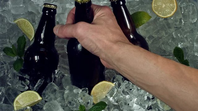 4k Shot of Cold Ice Cubes and Hand Taking Beer Bottle
