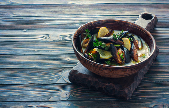 Mussels in clay pot over dark  wood background