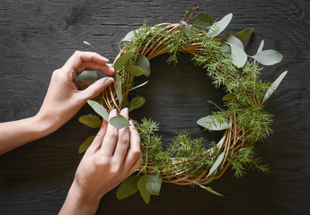 Hands making a wreath from eucalyptus and fir tree