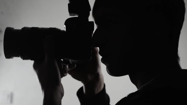 Photographer Silhouette close-up. Man takes pictures with DSLR camera.