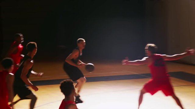 Basketball players passing the ball during a game and making a basket