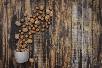 Hazelnuts and walnuts  in bowl on brown wooden table