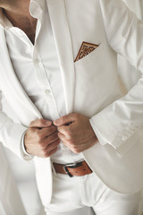 Elegant young handsome man with a beard in a white classic suit.