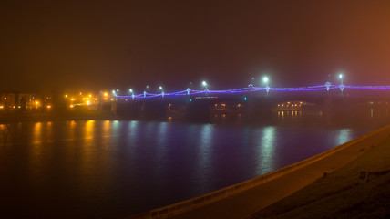 Novovolzhsky bridge over the Volga River in the fog and with night lighting. Built in 1956.